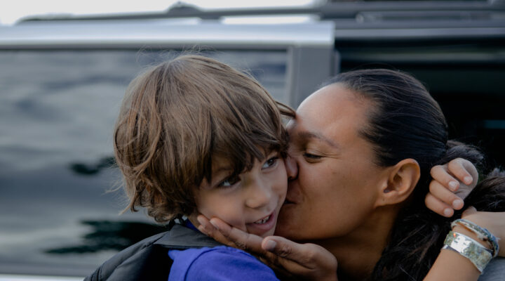 A mother kisses her son on the cheek
