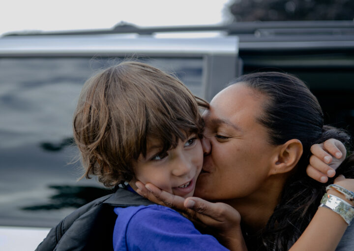 A mother kisses her son on the cheek