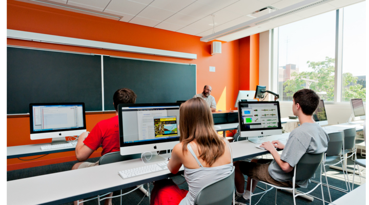 Students sit in a classroom looking at computers