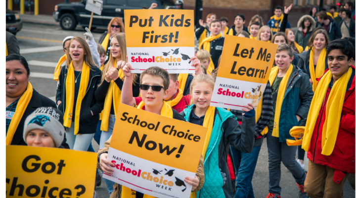Students hold up signs that say "Put Kids First!" for National School Choice Week