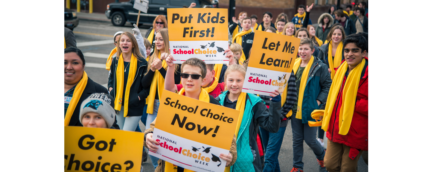 Students hold up signs that say "Put Kids First!" for National School Choice Week