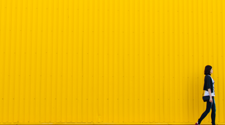 A woman walks in front of a bright yellow wall