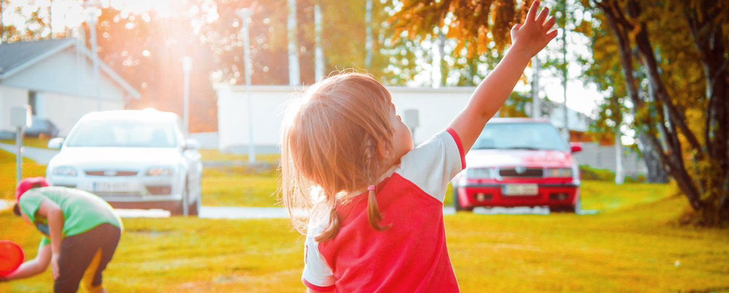 A little girl reaches towards a tree