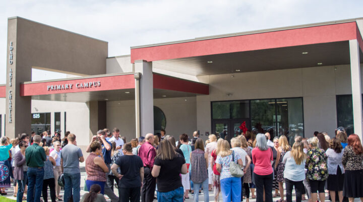 People stand in front of Idaho Arts Charter School for the ribbon cutting