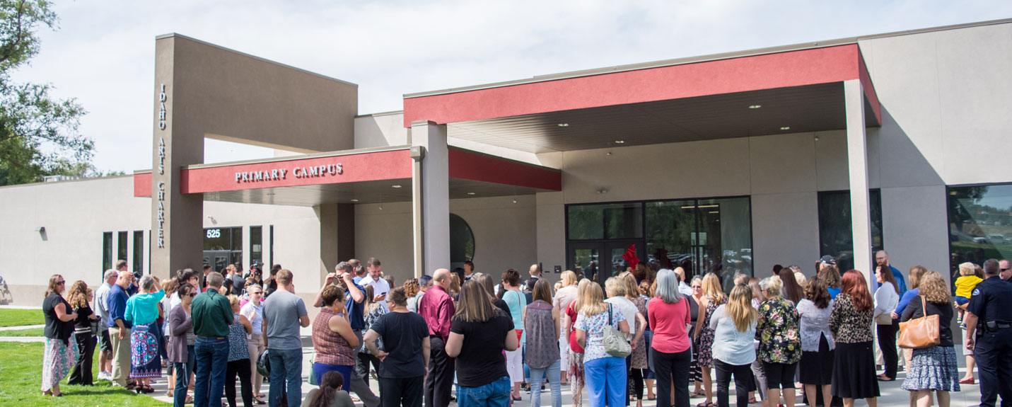 People stand in front of Idaho Arts Charter School for the ribbon cutting