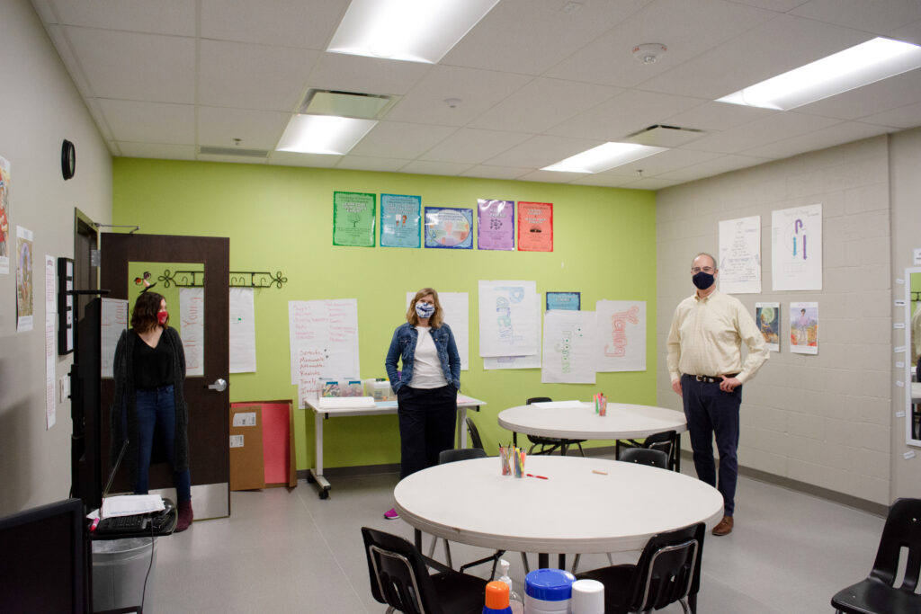 Three people standing in a classroom