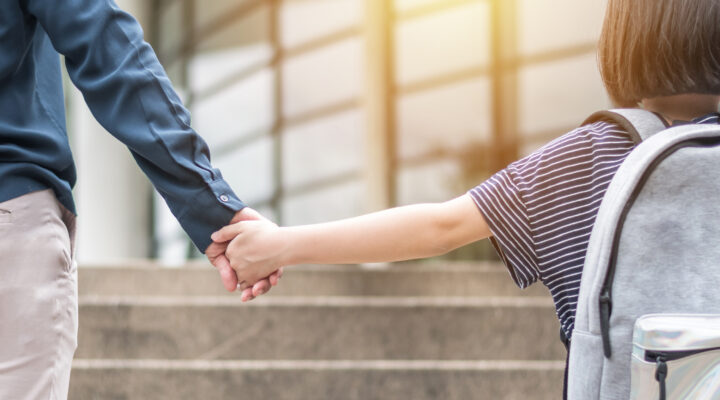 A parent holding their child's hand to school