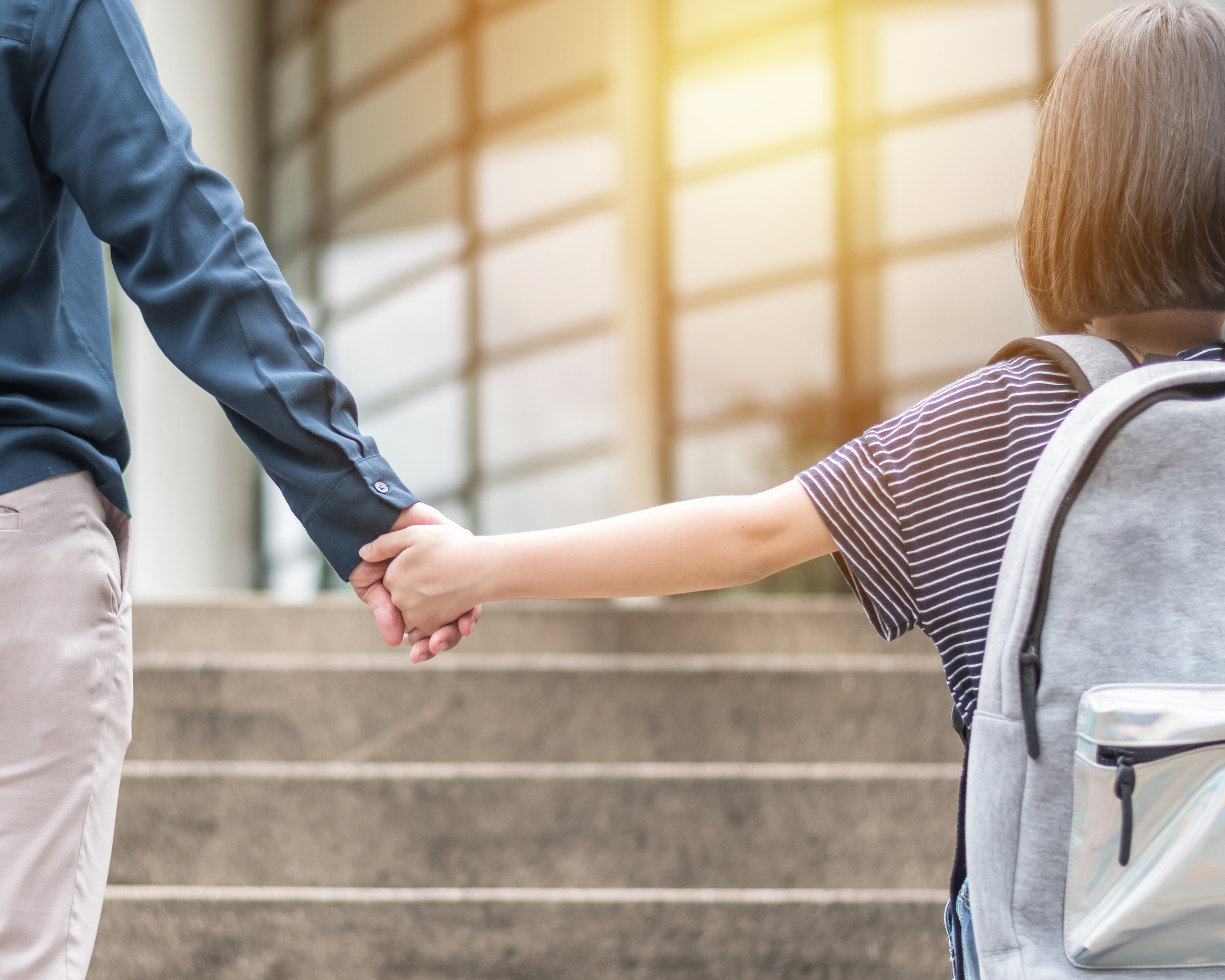 A parent holding their child's hand to school