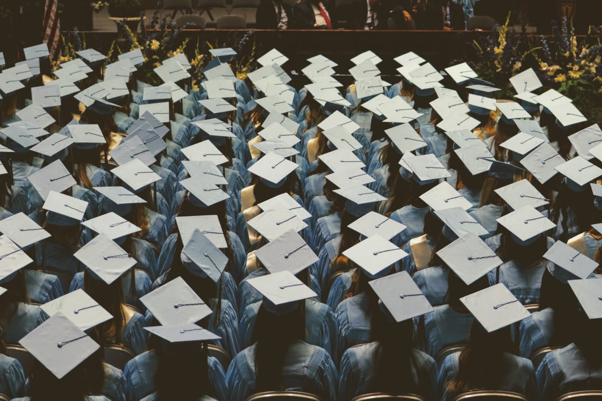 Students sit at a graduation ceremony wearing their caps and gowns