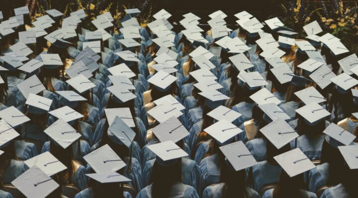 Students sit at a graduation ceremony wearing their caps and gowns