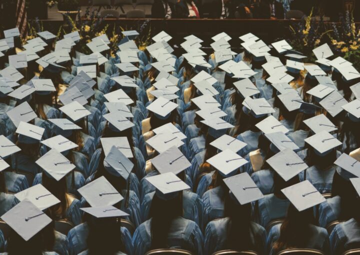 Students sit at a graduation ceremony wearing their caps and gowns