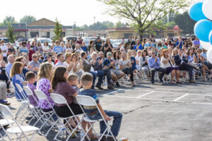 a crowd is seated around the front of the school.