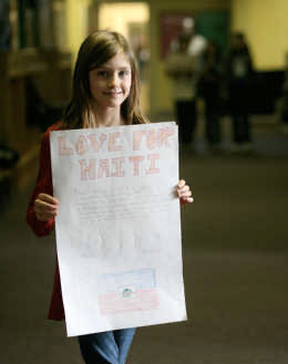 Ana Earl stands with a poster she made for a fundraiser at Anser