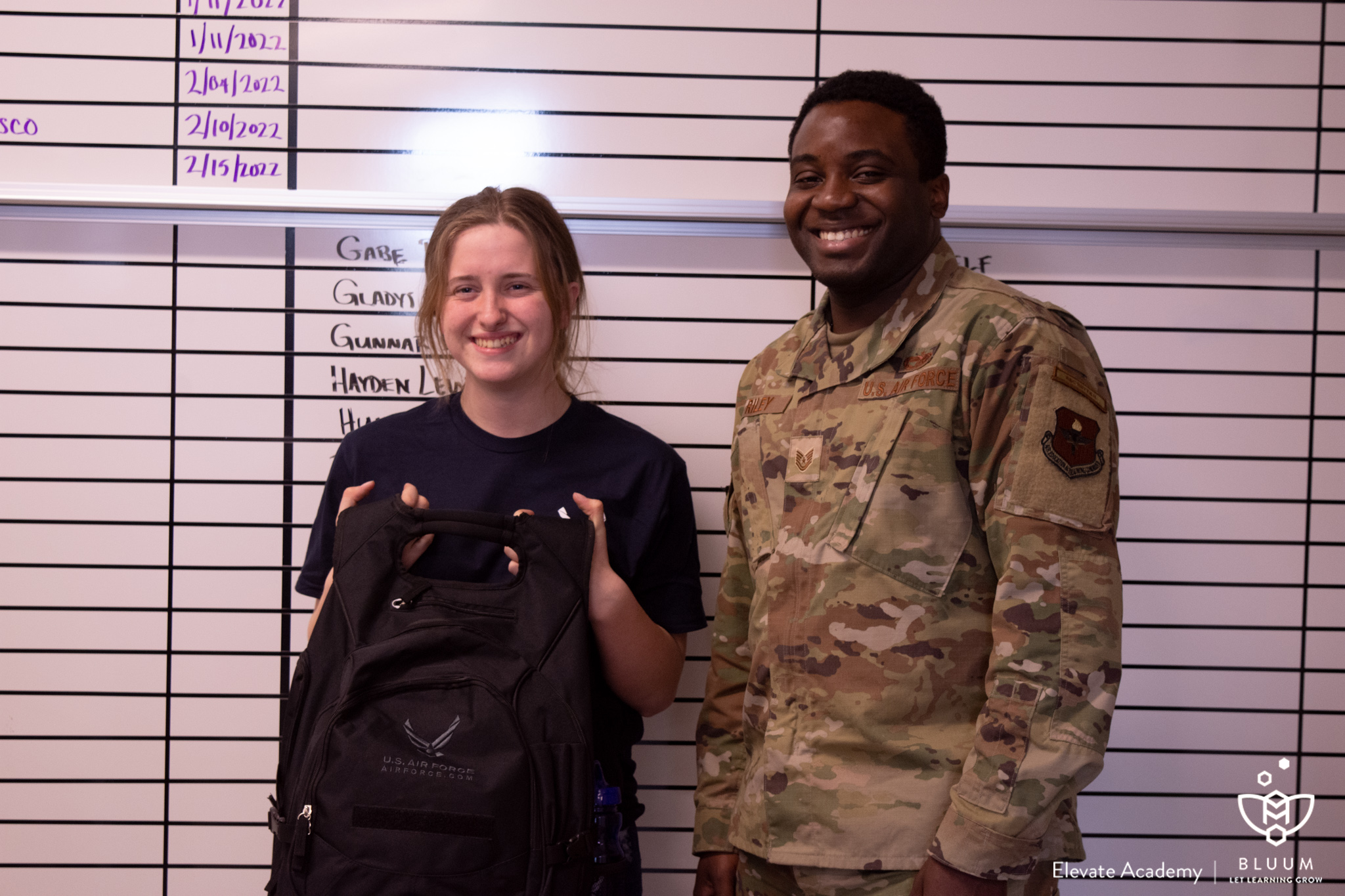 Senior Megan Benson stands in front of the ‘80 for 80’ board with her new Air Force backpack, next to Technical Sargent in the US Air Force and Nampa Area Air Force Recruiter Paul Riley.